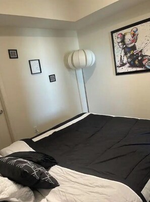 Un dormitorio con una cama, una lámpara blanca y un cuadro en la pared.