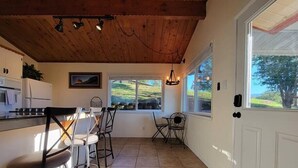 Une cuisine avec un coin repas, un plafond en bois et de grandes fenêtres.