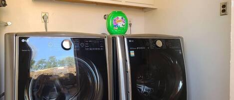 Two front-loading LG washing machines in a laundry room with a cabinet above.