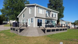 A two-story house with a covered deck and a staircase leading to the entrance. - 10 Mile View on Lake Murray, SC, Putting Green, Hot Tub, Lake Edge Fire Pit (Gilbert)