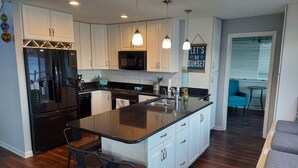 A modern kitchen with white cabinets, a black refrigerator, stainless steel appliances, and a central island with bar stools. - 10 Mile View on Lake Murray, SC, Putting Green, Hot Tub, Lake Edge Fire Pit (Gilbert)