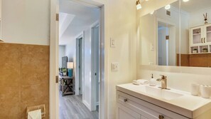 A modern bathroom with a large mirror, a sink, and a vanity. - Flagler's Oasis by Avantstay Tropical Key West Escape Private Pool Month Long Stays Only (Key West)
