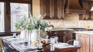 A dining table set with plates, glasses, and a centerpiece of greenery. - Klamath by Avantstay Premier Lakeside Cabin w/ Spa, Fire Pit & Lake Views (Bend)
