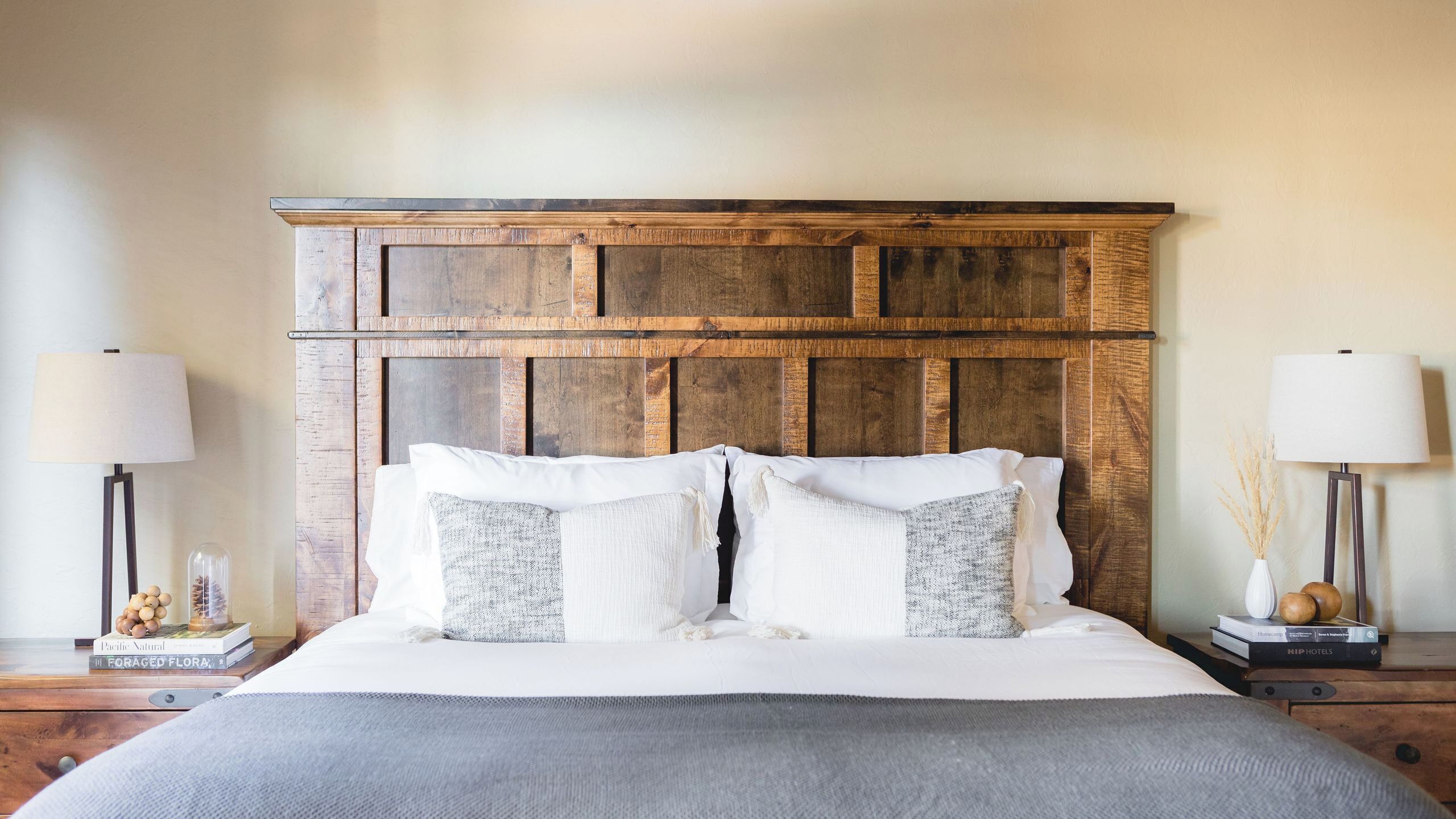 A bed with a wooden headboard, two bedside tables, and lamps.
