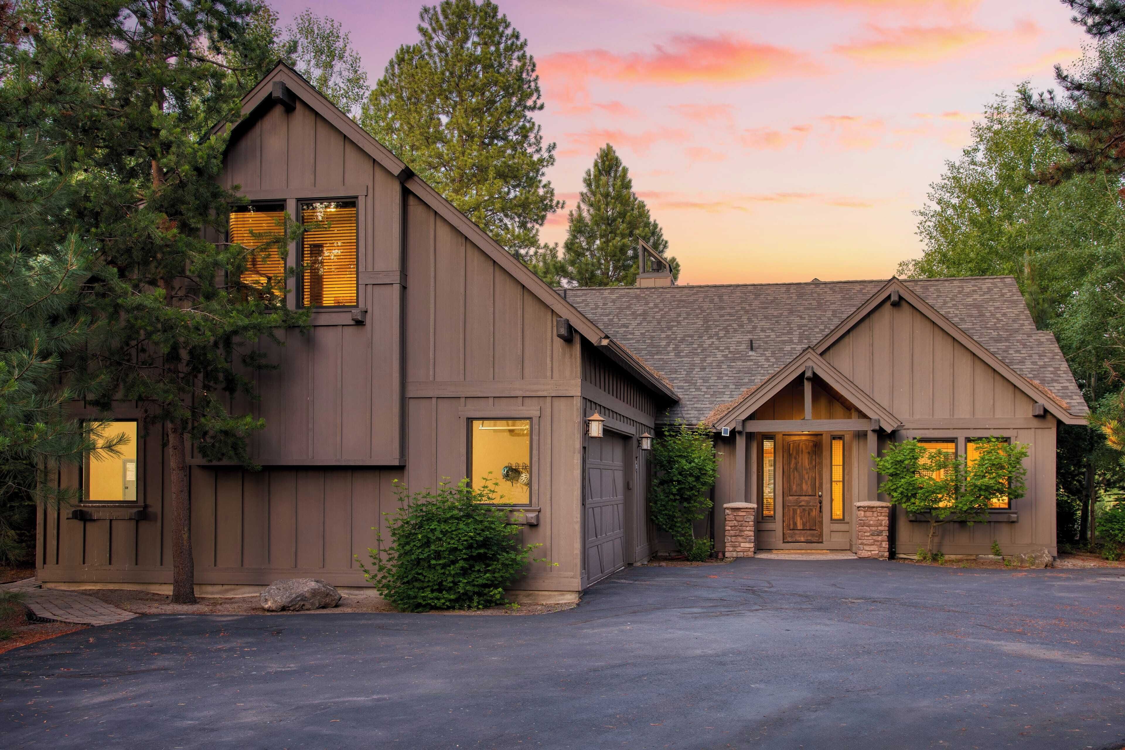A two-story house with a steeply pitched roof, a front garage, and a driveway leading to the entrance.