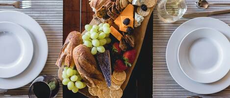 Een charcuterieplank met diverse kazen, fruit en crackers op een houten plank.