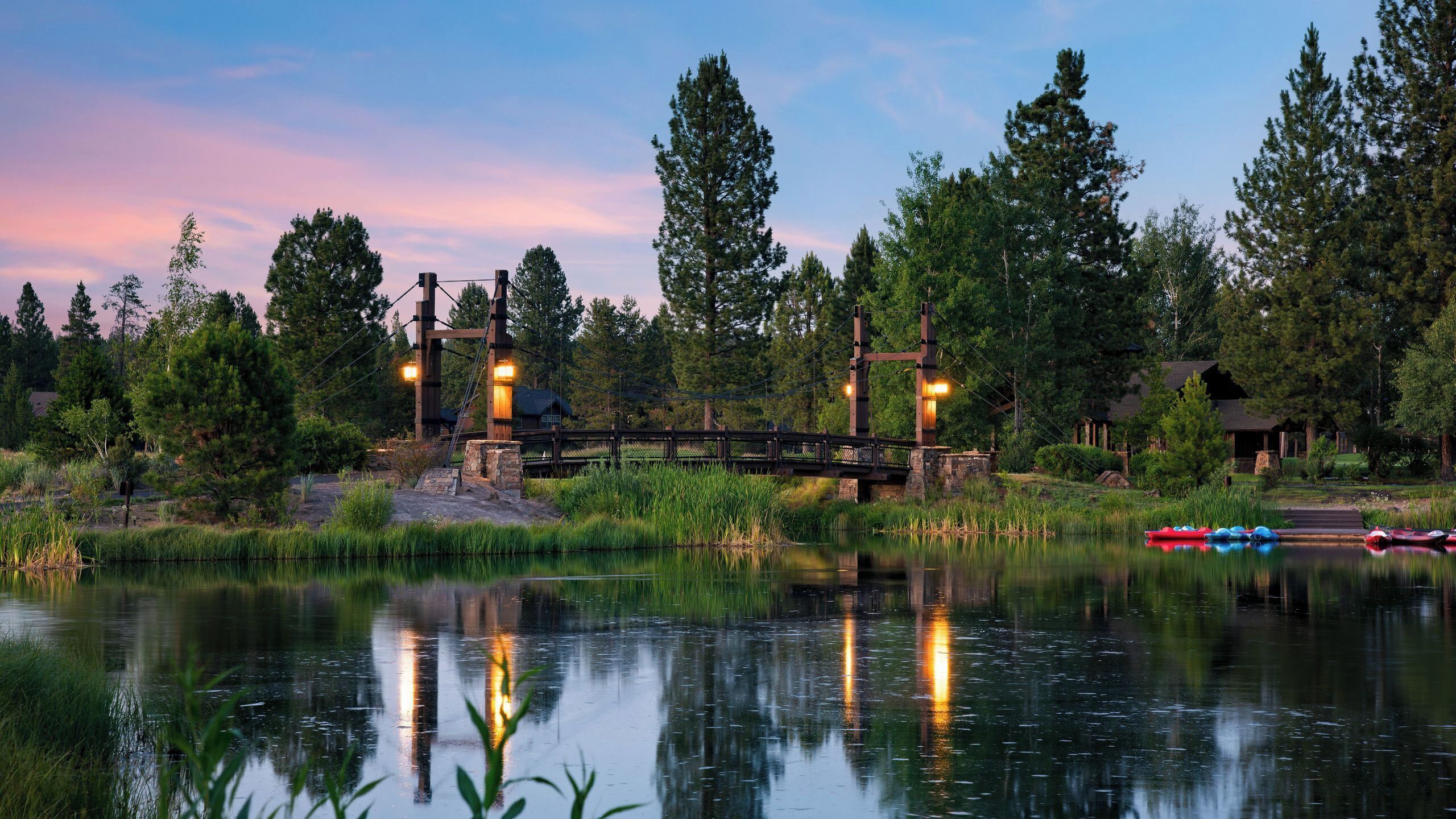 A tranquil lakeside setting with a wooden bridge, stone steps, and a row of canoes.