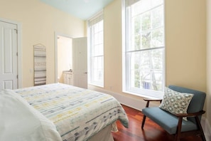 A bedroom with a large bed, a chair, and a window.