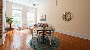 A dining area with a round table, four chairs, a vase with flowers, and a wall-mounted decorative piece. - Bright & Sunny CBD FQ Convention Center Area Condo (New Orleans)
