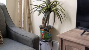 Uma sala de estar com um sofá cinza, um armário de madeira, uma planta em vaso e um mapa na parede.