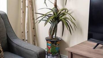 A living room with a grey sofa, a wooden cabinet, a potted plant, and a wall map.