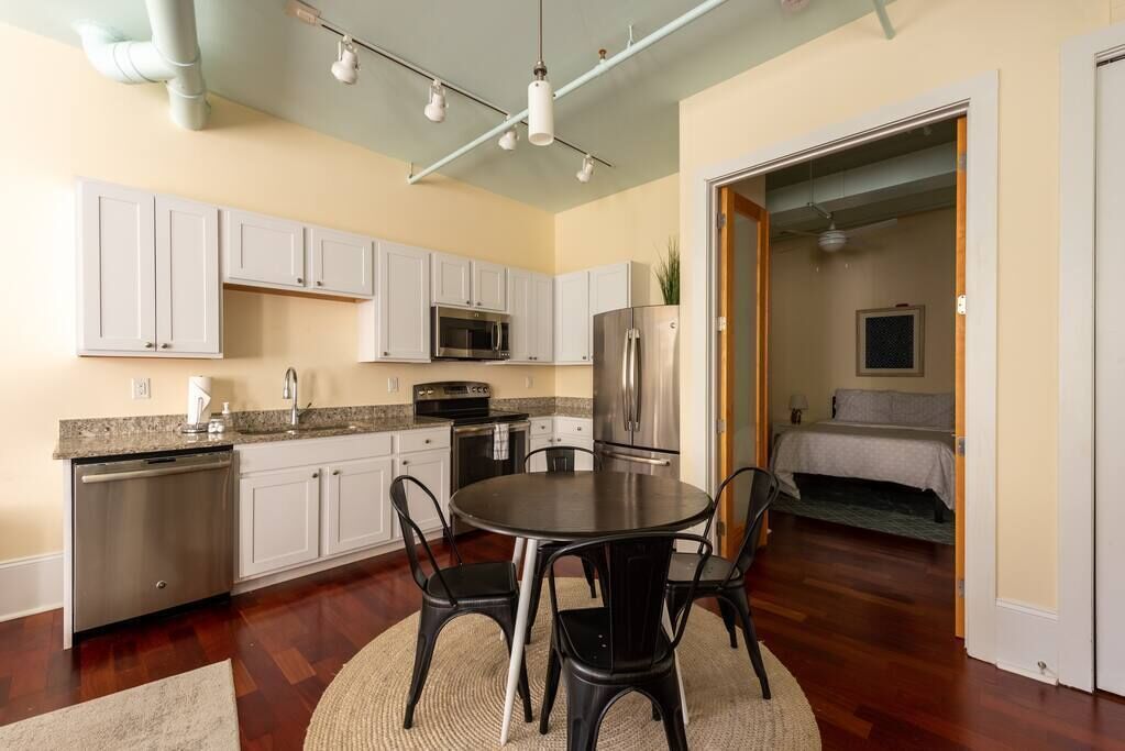 A compact kitchen with white cabinets, a stainless steel refrigerator, and a microwave.