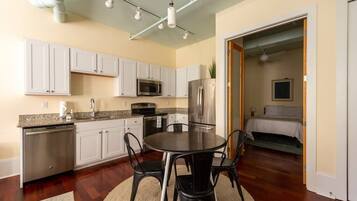 A compact kitchen with white cabinets, a stainless steel refrigerator, and a microwave.