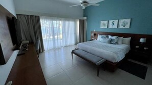 Une chambre d’hôtel avec un lit, un banc, un ventilateur de plafond et un téléviseur.