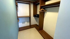 Un couloir avec une armoire en bois, un portant et une porte donnant sur une autre pièce.