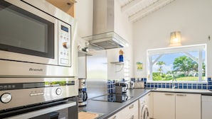 A modern kitchen with a Brandt microwave, a coffee maker, and a washing machine. - Villa Green Caraibes, pool and view on the international golf of St-François (Saint Francois)