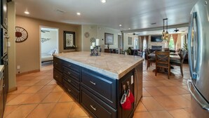 A spacious kitchen with a large island, dark cabinetry, and a stainless steel refrigerator.