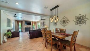 A spacious dining area with a wooden table and chairs, a fireplace, and decorative wall art.