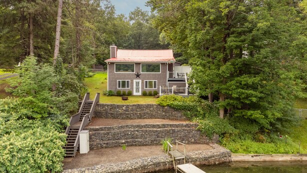 A two-story house with a dock extending into a pond, surrounded by lush greenery. - Lakefront, Kayaks, Firepit, great baseball stay! (Maryland)
