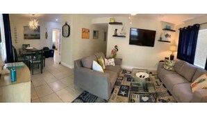 A living room with a sofa, coffee table, and a dining area with chairs and a table.