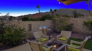 An outdoor patio with wicker furniture, a fire pit, and a barbecue grill.