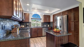 A modern kitchen with granite countertops, stainless steel appliances, and wooden cabinets.