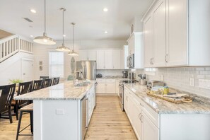 A modern kitchen with white cabinets, a marble island, and pendant lighting. - Aquamarine by Avantstay 7BR w/ Pool, Hot Tub, Outdoor Dining, BBQ & Near Beach (Miramar Beach)