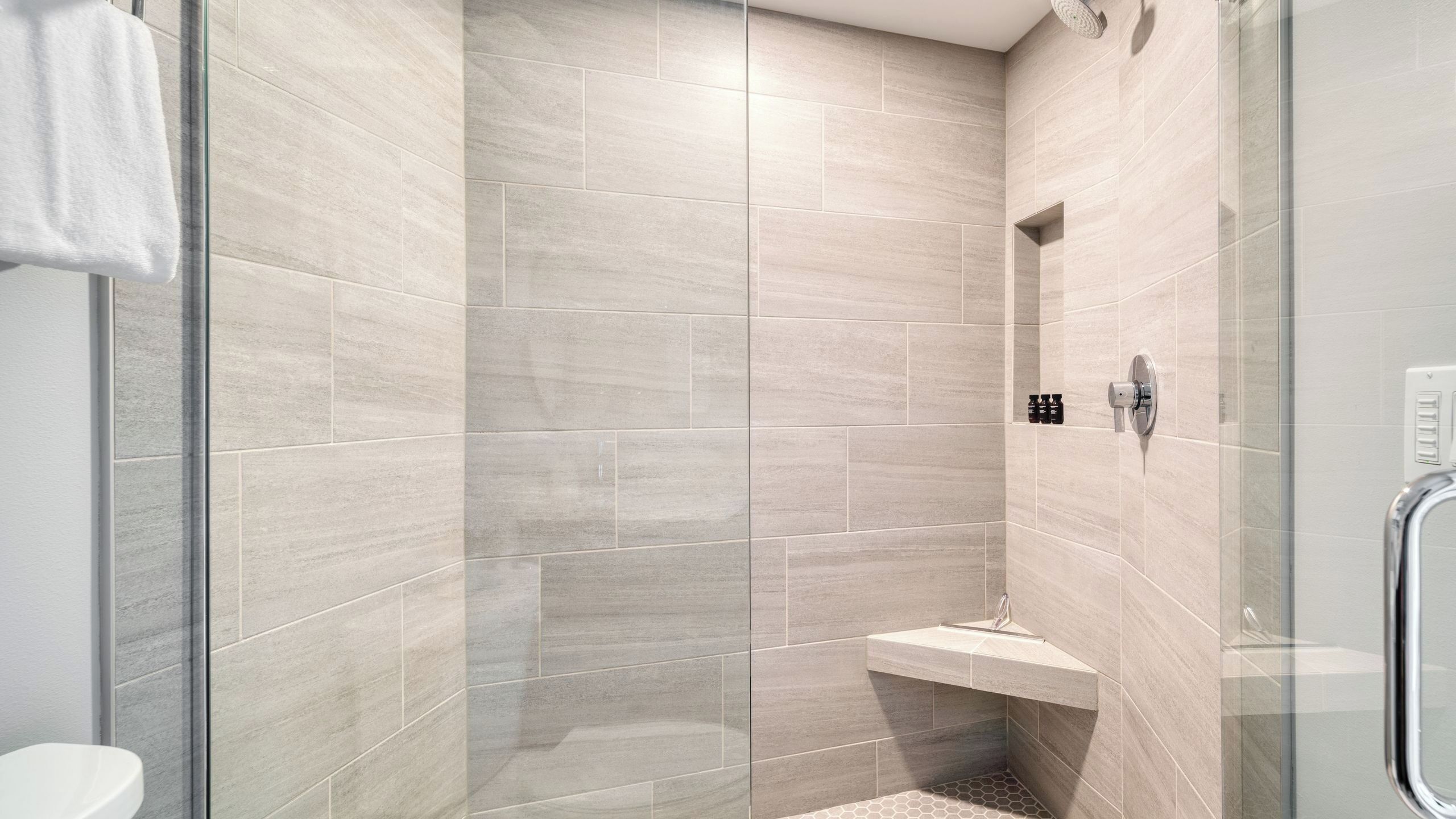 Eine moderne Dusche mit Glastür, Sitzbank und Bedienfeld.