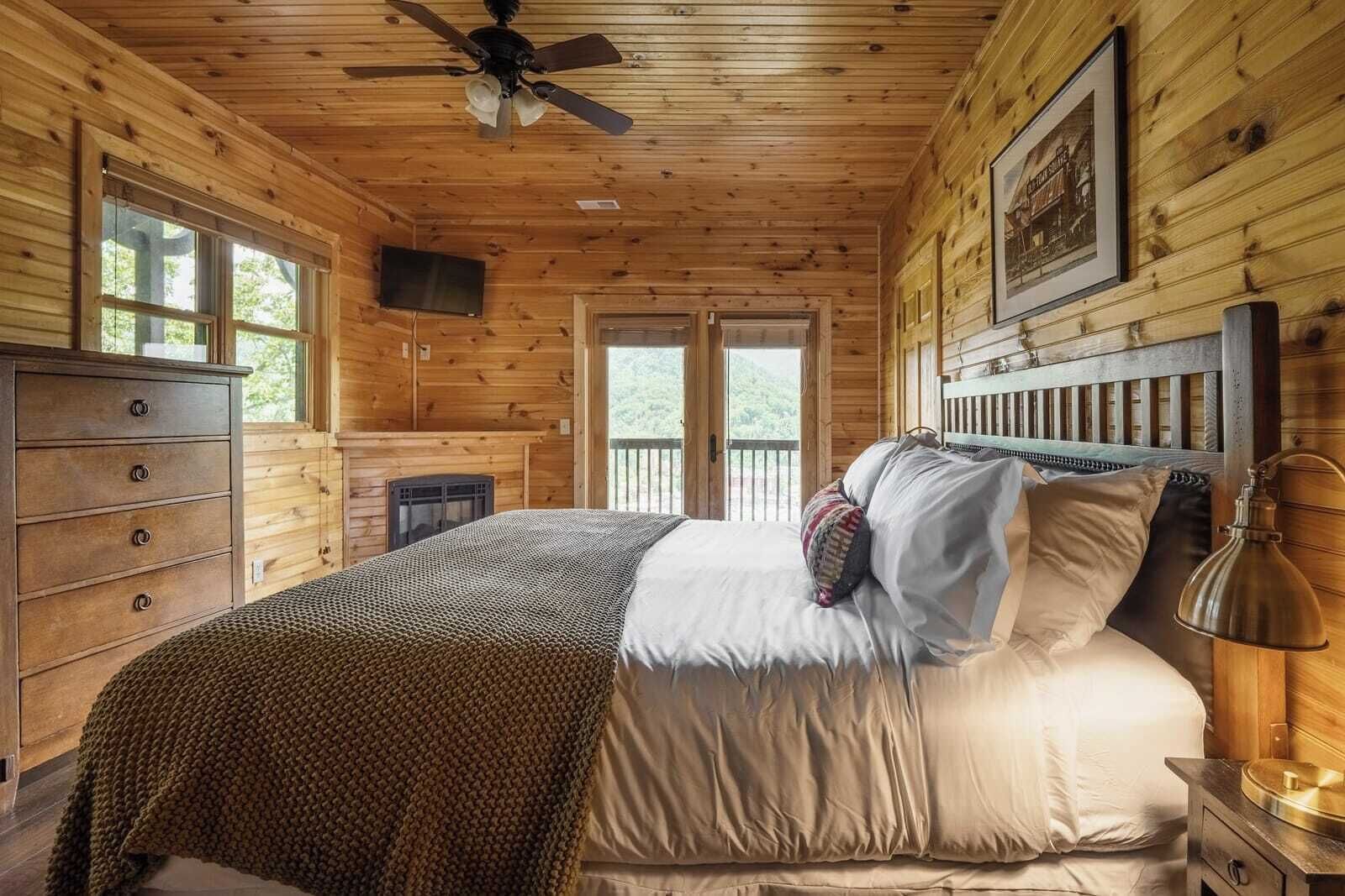 Een houten slaapkamer met een bed, een kaptafel en een open haard.