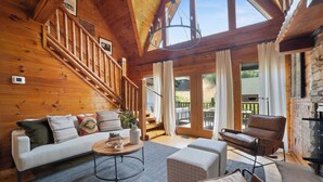 A wooden interior with a staircase, a sofa, a coffee table, and a leather chair. - Tennessee Blue by Avantstayheart of Pigeon Forge! (Pigeon Forge)