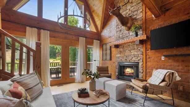 A cozy log cabin interior with a fireplace, wooden beams, a mounted deer head, and a comfortable seating area. - Tennessee Blue by Avantstayheart of Pigeon Forge! (Pigeon Forge)