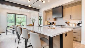 A modern kitchen with a large island, bar stools, and a view of the outdoors. - Encore by Avantstayminutes From the Slopes in PC! w/ Hot Tub (Park City)