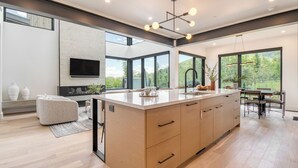 A modern kitchen with a large island, built-in appliances, and large windows offering views of the outdoors. - Encore by Avantstayminutes From the Slopes in PC! w/ Hot Tub (Park City)