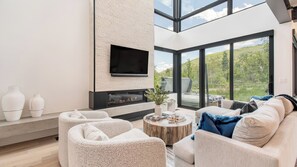 Uma sala de estar moderna com lareira, assentos confortáveis e uma grande janela com vista para o exterior.