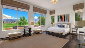 A spacious bedroom with a large bed, a desk, and a view of a golf course.