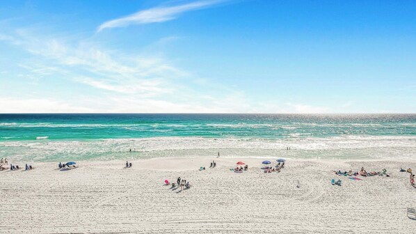 Una playa con gente, sombrillas y un cielo despejado.