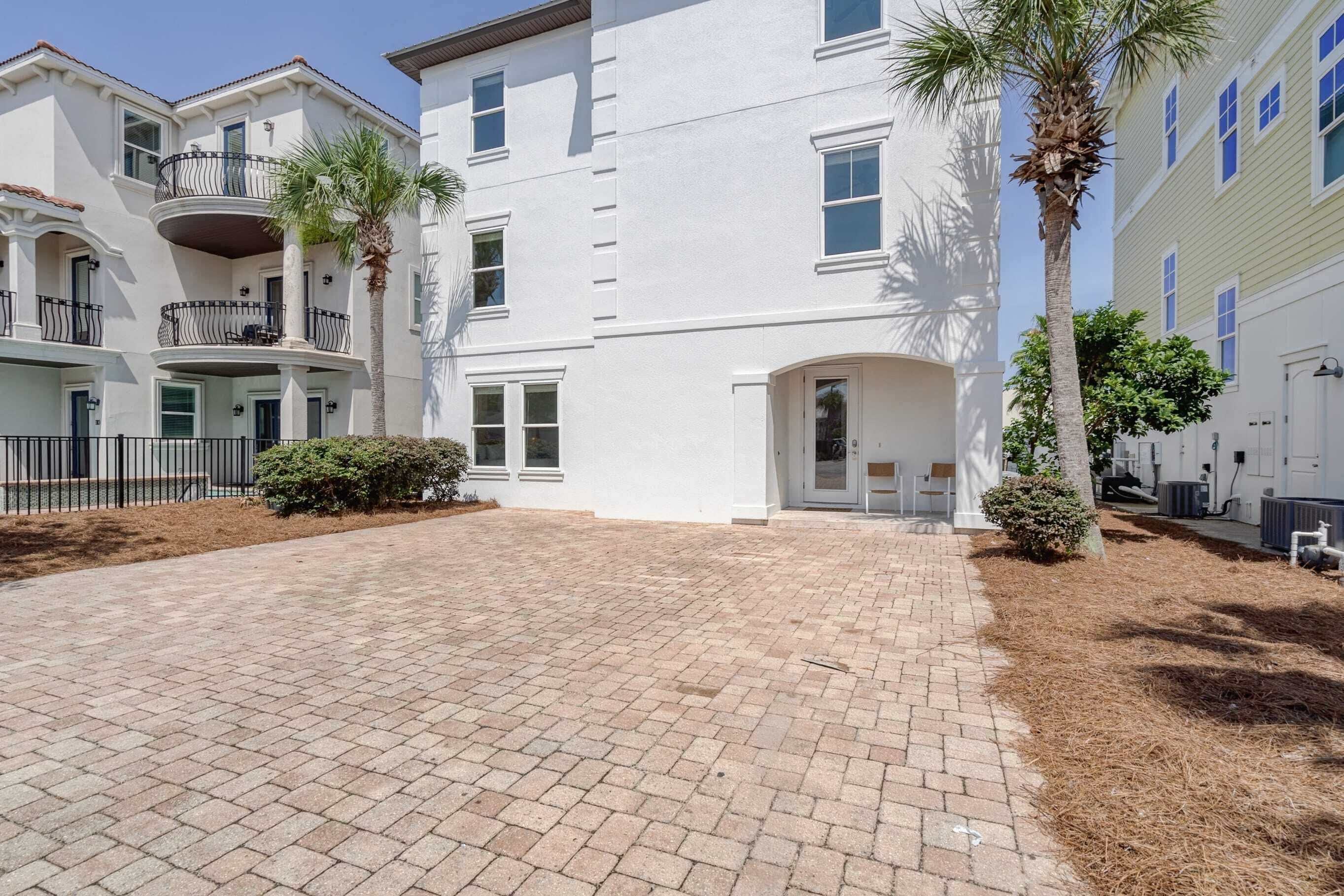 A multi-story residential building with a paved courtyard, balconies, and palm trees.