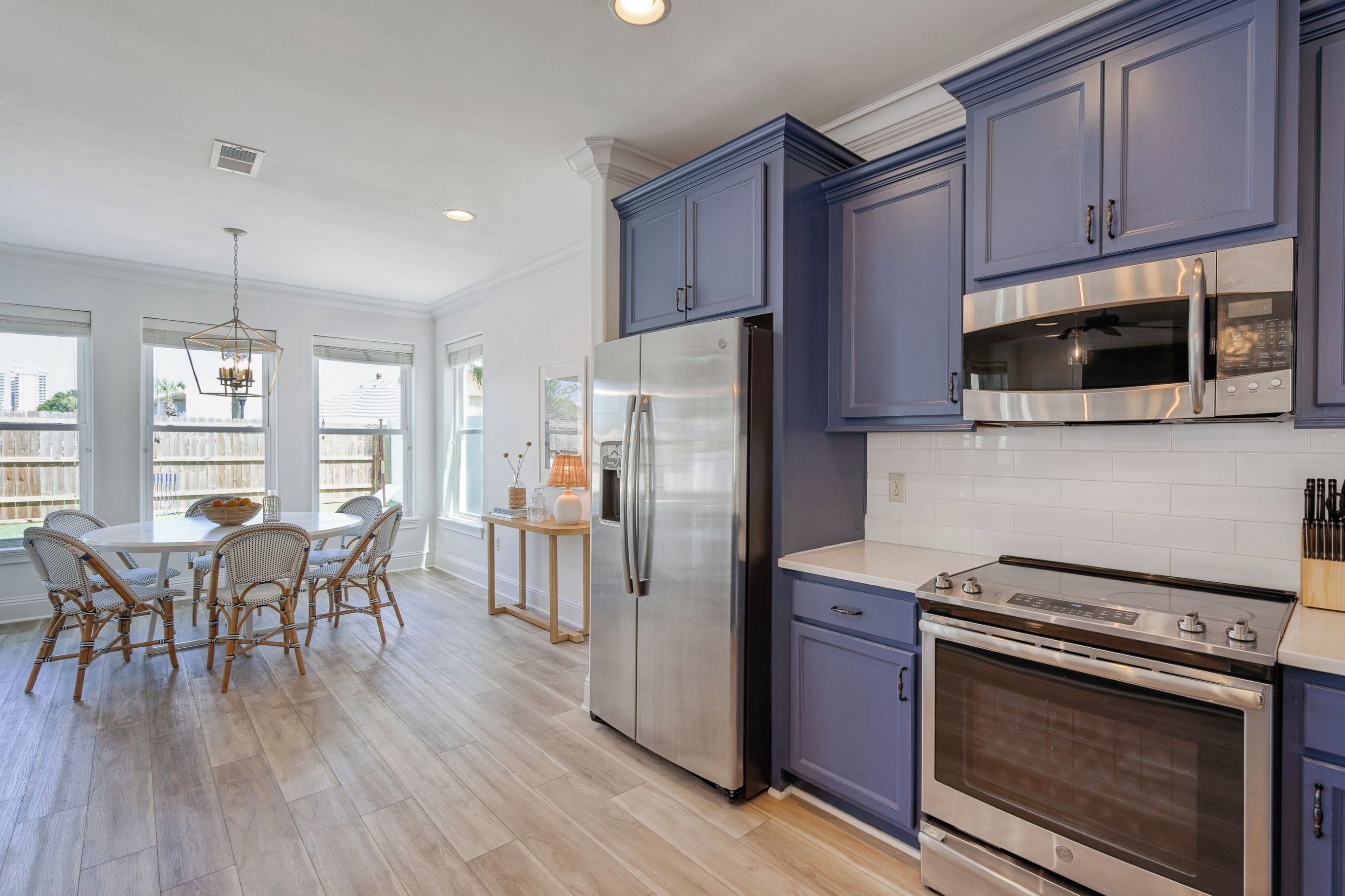 A kitchen with a large refrigerator, microwave, stove, and blue cabinets.