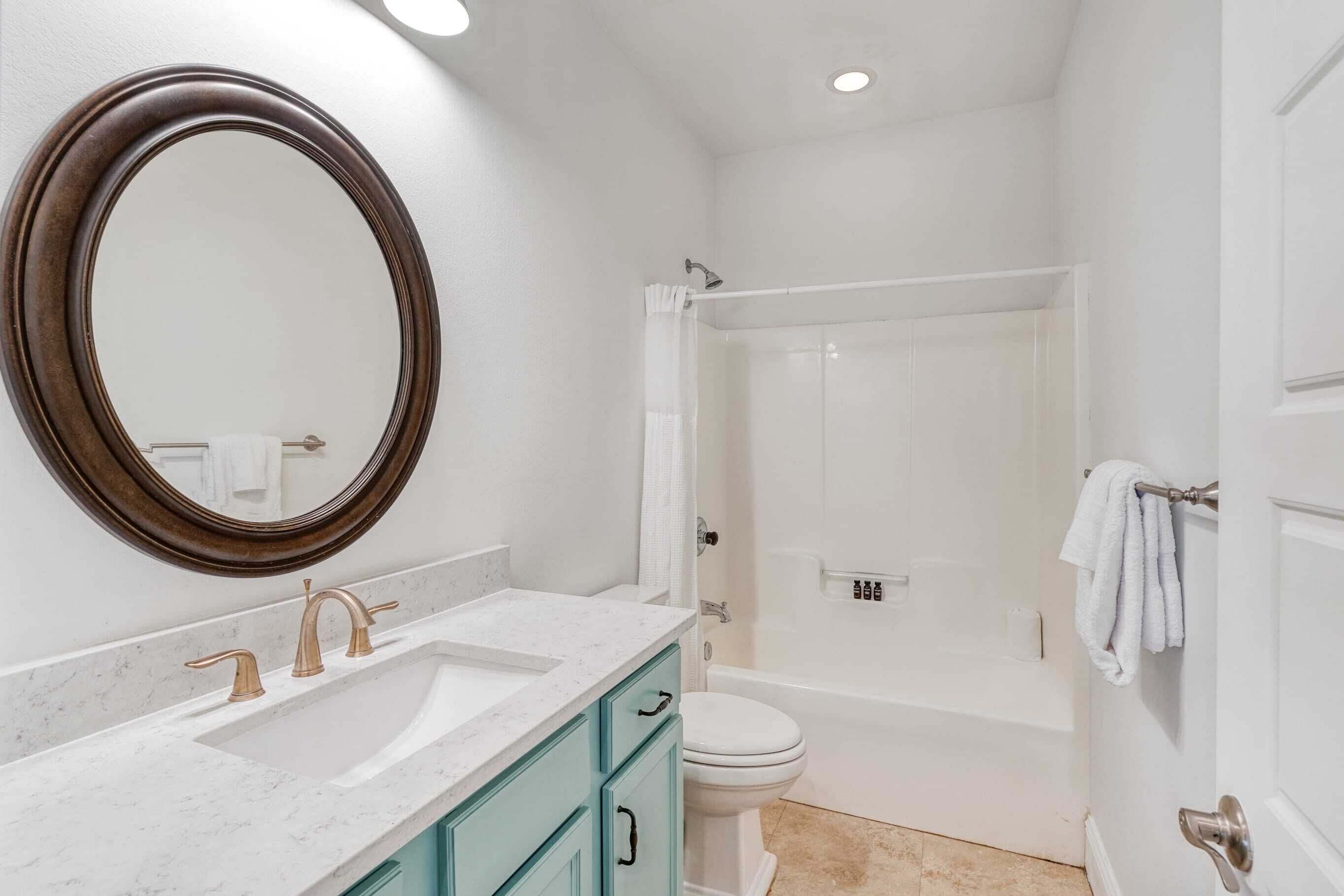 Une salle de bain avec un grand miroir, un lavabo à deux robinets, des toilettes et un espace douche.