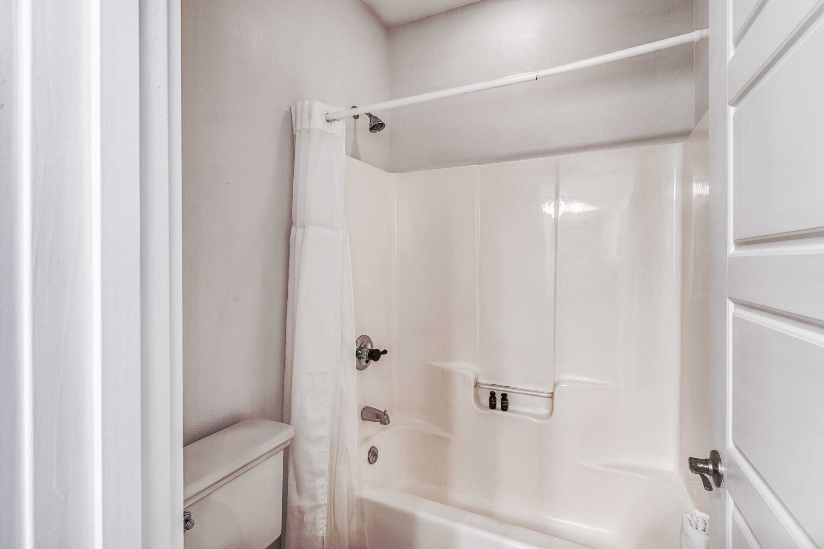Une salle de bain avec une baignoire blanche, des toilettes et un rideau de douche.