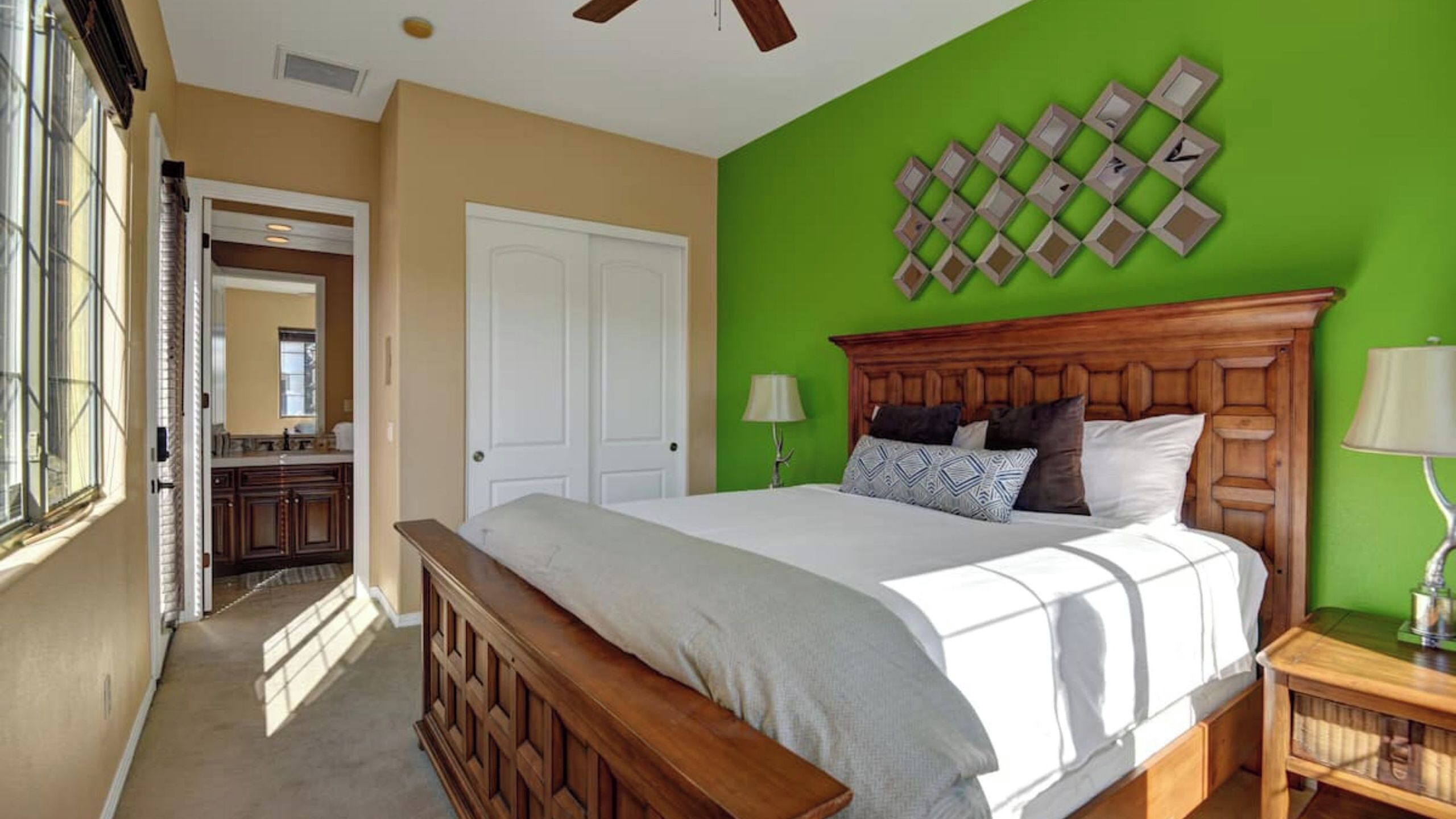 A bedroom with a bed, a nightstand, a lamp, a dresser, and a mirror.