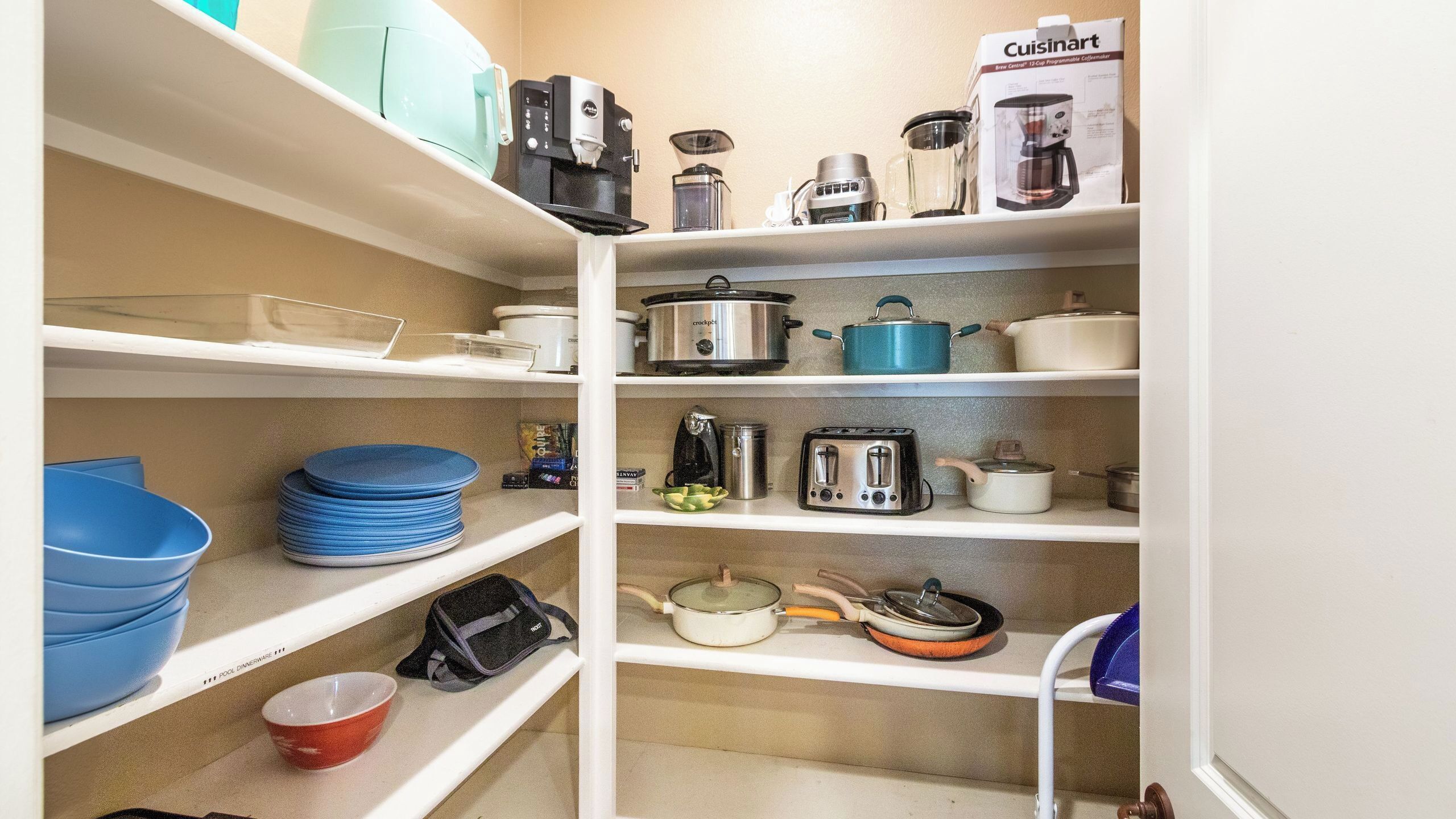 Una cocina con estantes que contienen utensilios de cocina, incluyendo ollas, sartenes y una cafetera.