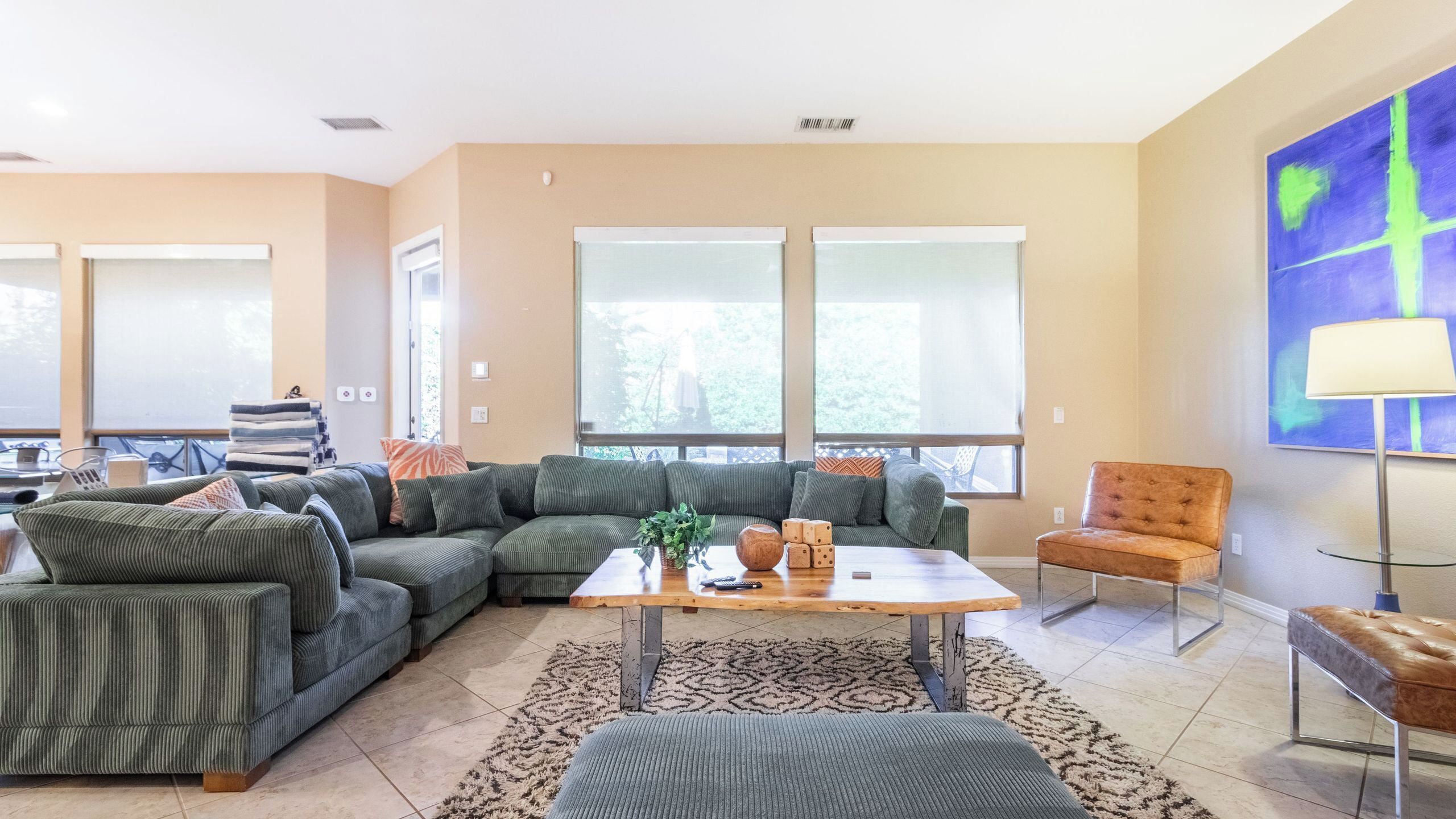 Una sala de estar con un sofá modular, una mesa de centro, un sillón y un cuadro en la pared.