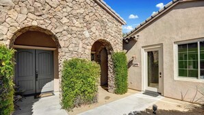 A stone building with two arched doorways, a small patio, and a window. - Songbird by Avantstay Pool, Spa & Firepit + Tons of Outdoor Seating (Indio)