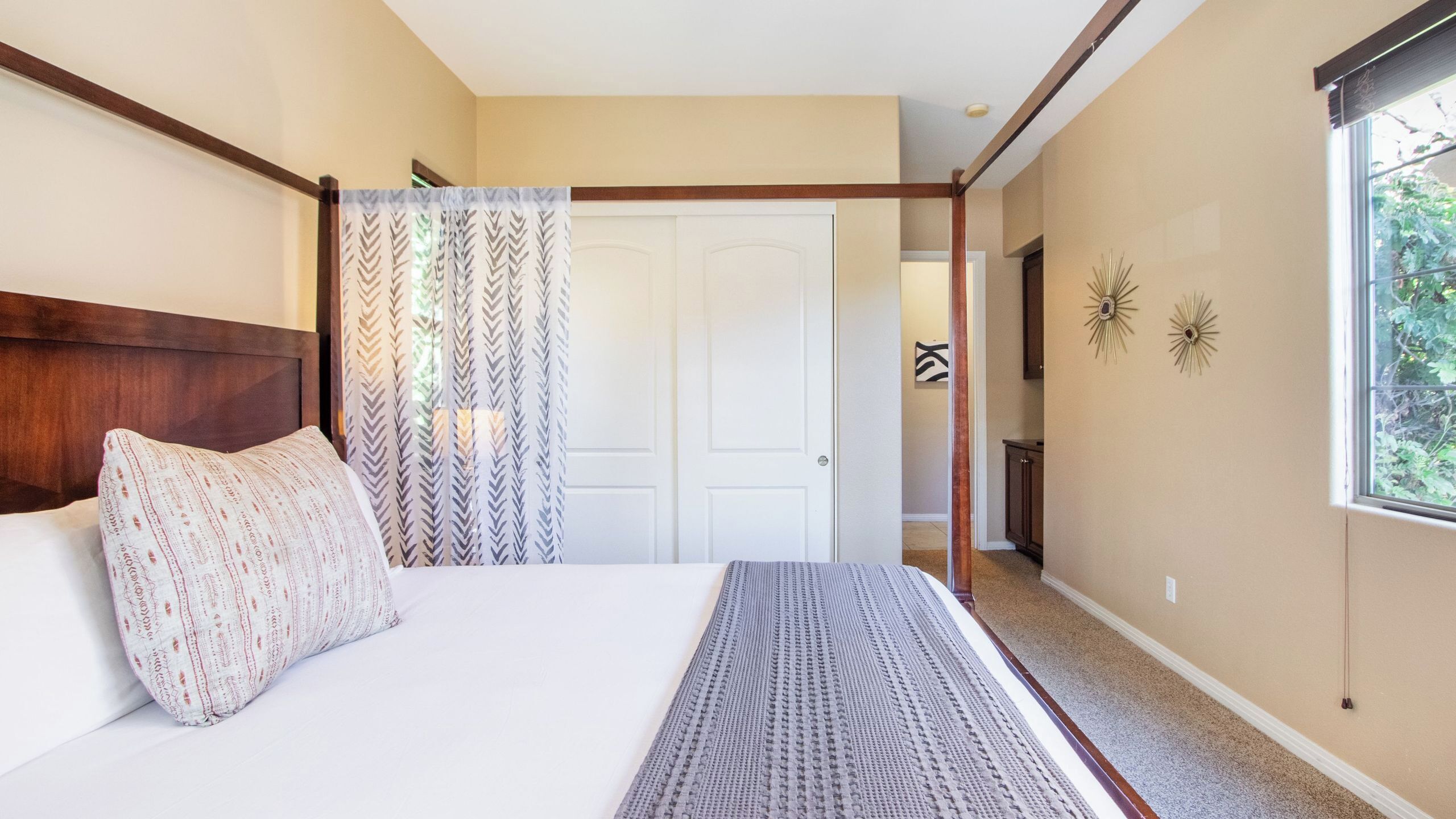 A bedroom with a bed, a window, a door, and a hallway.