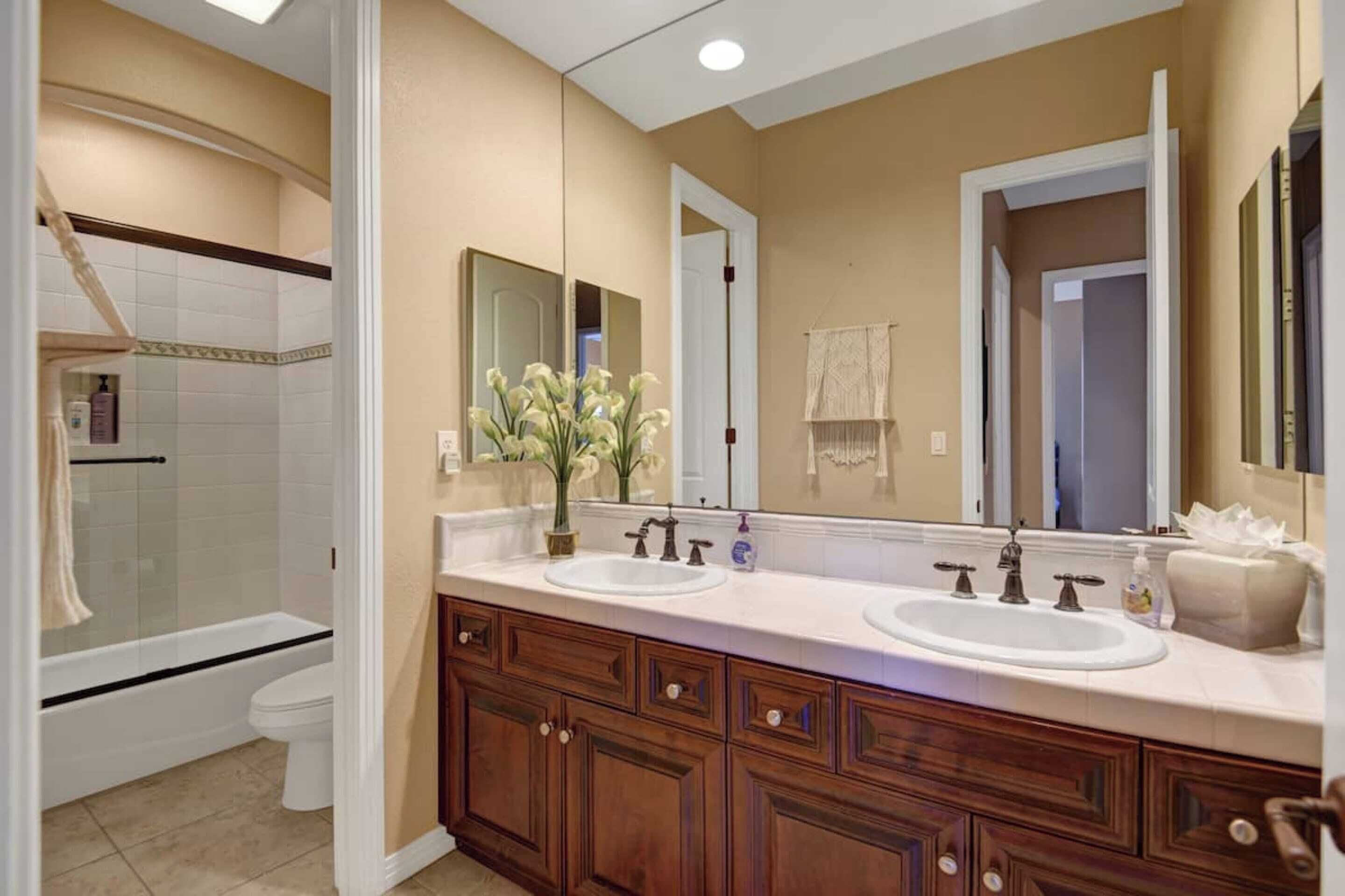 A bathroom with two sinks, a shower, and a large mirror.