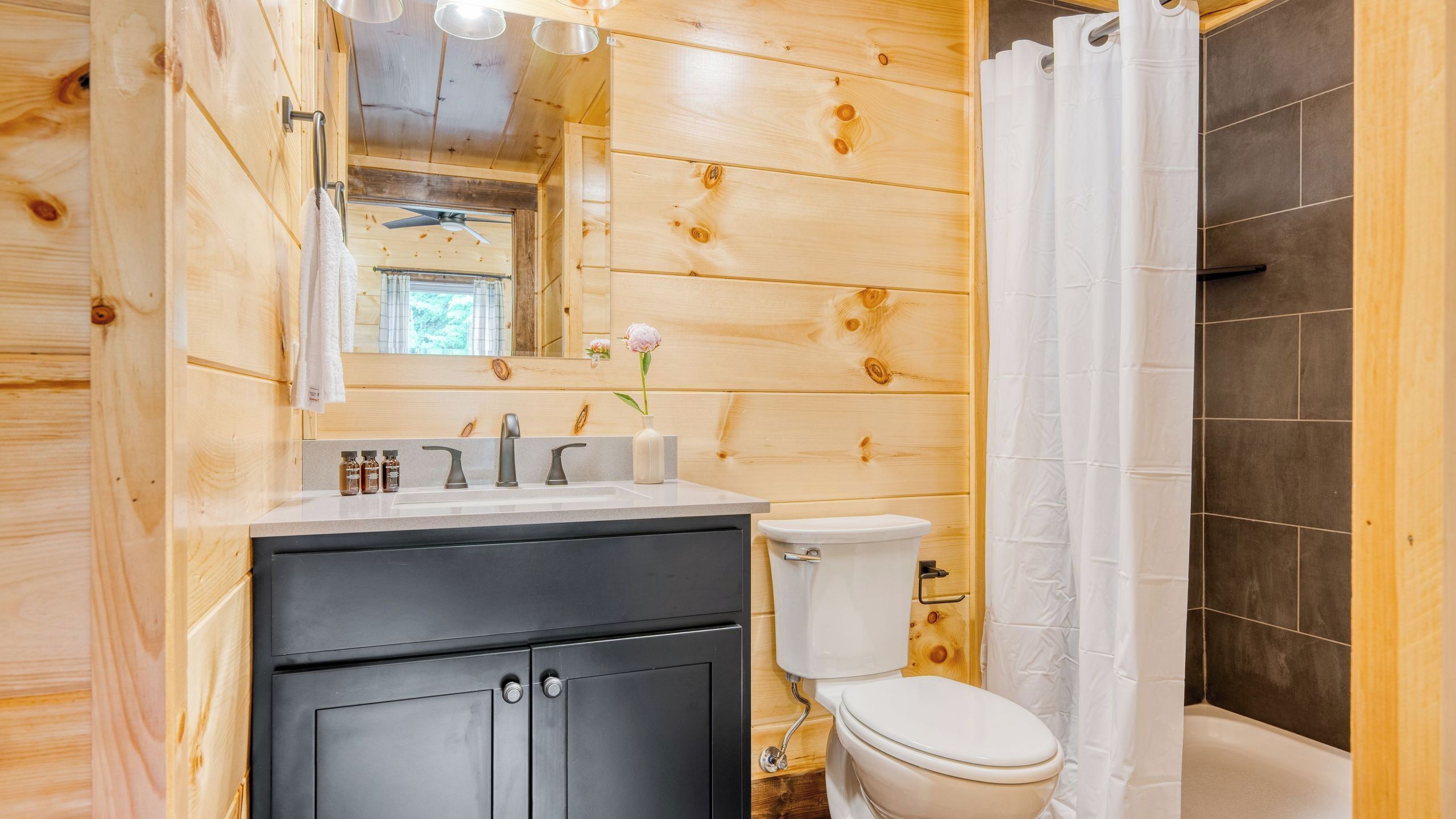Ein Badezimmer aus Holz mit Waschbecken, Toilette und Duschvorhang.