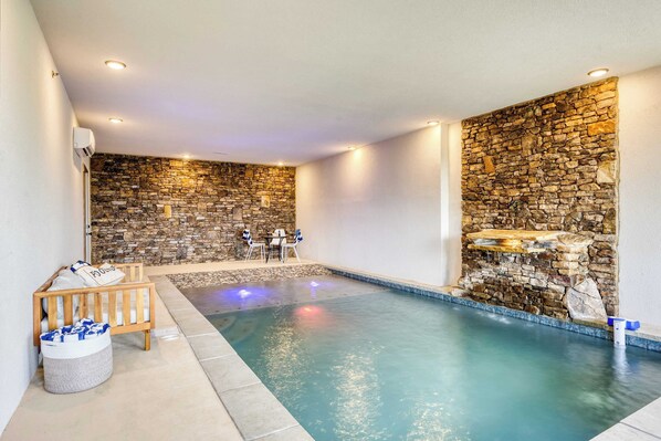 Una piscina con paredes de piedra y un banco, rodeada por un suelo de baldosas.