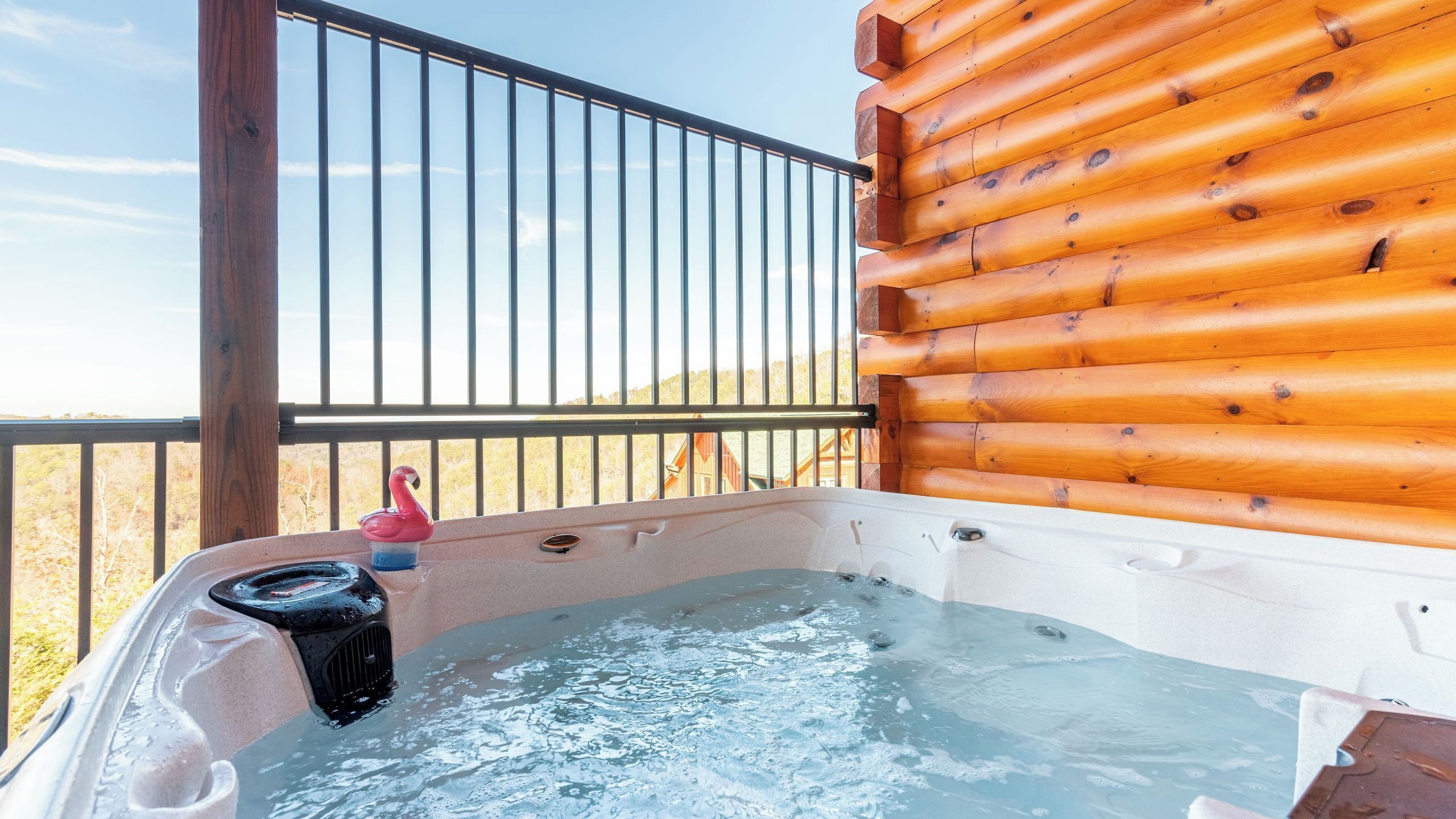 Un jacuzzi con cubierta de madera y barandilla de metal, con vista a un paisaje montañoso.