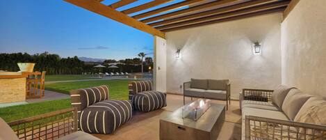 An outdoor patio with a pergola, seating area, and a view of a golf course.